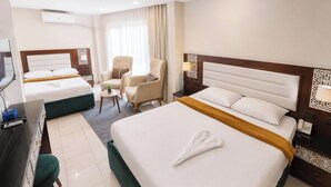 A hotel room with two beds, a desk, a chair, a TV, and a window with curtains. - Karnak Hotel Luxor (Luxor)