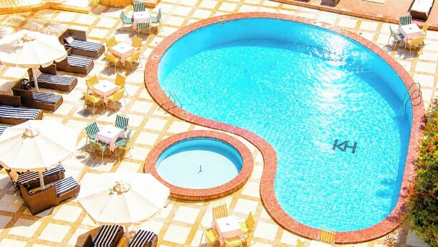 A swimming pool with sun loungers and umbrellas, surrounded by a tiled patio. - Karnak Hotel Luxor (Luxor)