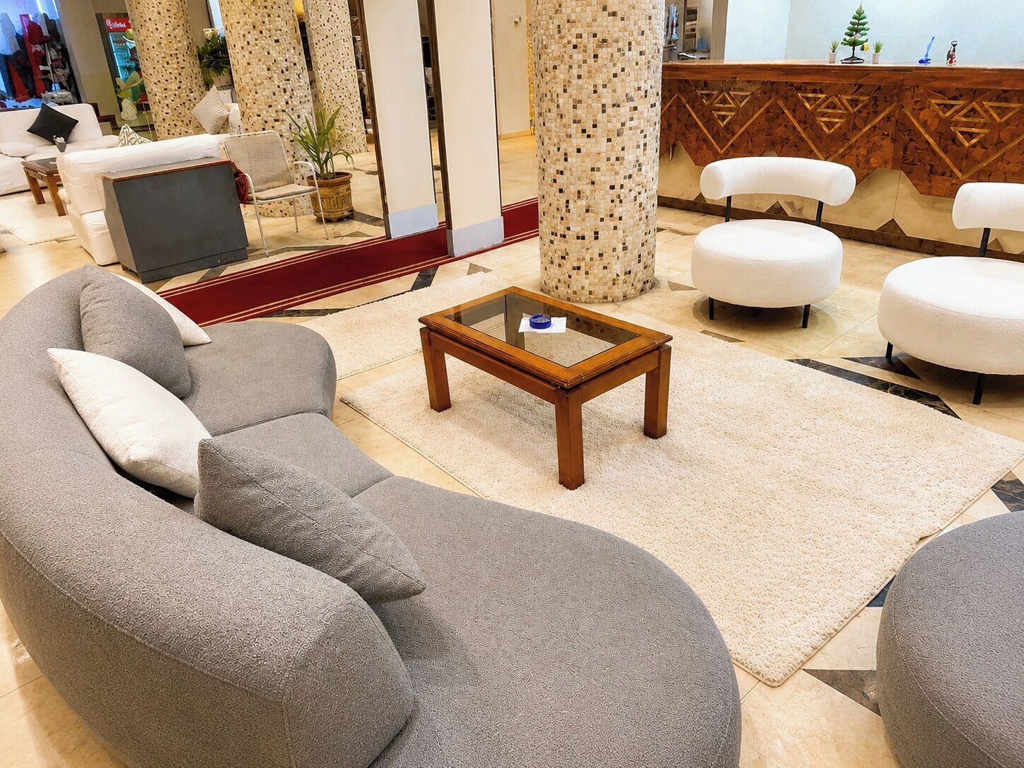 A modern living room with a sectional sofa, a glass-top coffee table, and a reception desk with decorative elements.