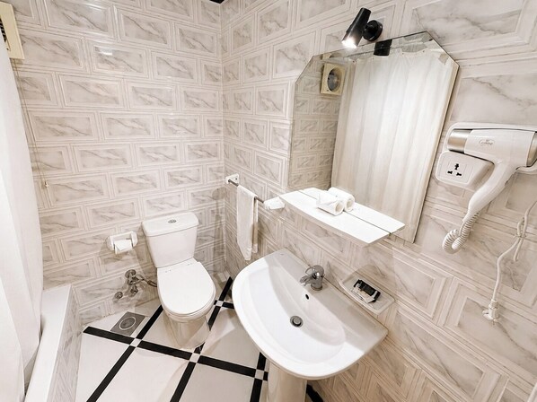 Un baño con inodoro, lavamanos y espejo.