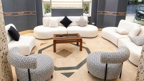 A modern living room with a sofa set, two patterned armchairs, a coffee table, and a decorative chandelier. - Karnak Hotel Luxor (Luxor)