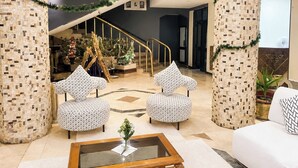 A lobby with two patterned armchairs, a glass coffee table, a staircase, and a Christmas tree. - Karnak Hotel Luxor (Luxor)