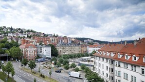 A cityscape with a mix of residential and commercial buildings, a road with vehicles, and a pedestrian walkway.