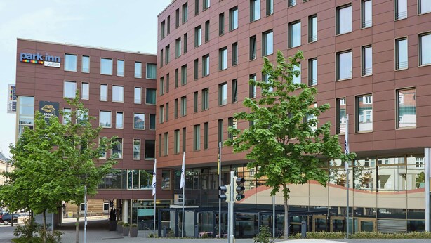 A modern building with multiple floors, featuring a 'Park Inn' sign on the facade.