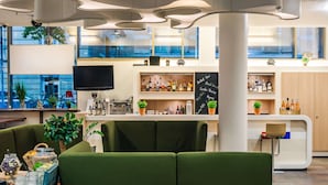 A modern bar area with green seating, a television, and a variety of bottles on shelves. - Park Inn by Radisson Stuttgart (Stuttgart)