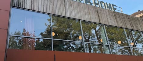 A building with a large sign reading 'B&B HOME' and a modern architectural design with large windows reflecting trees.