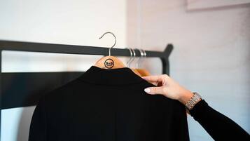 Een zwart shirt aan een houten hanger met een B&B Hotels logo, vastgehouden door een hand met horloge.