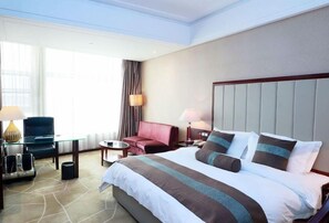 A hotel room with a large bed, a desk, a chair, and a sofa. - Xinhua Jianguo Hotel Jiujiang (Jiujiang)