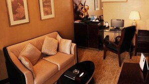 A hotel room with a sofa, a coffee table, a desk with a computer, and a chair. - Xinhua Jianguo Hotel Jiujiang (Jiujiang)
