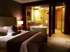 A hotel room with a bed, a bathroom with a bathtub, and a mirror. - Xinhua Jianguo Hotel Jiujiang (Jiujiang)