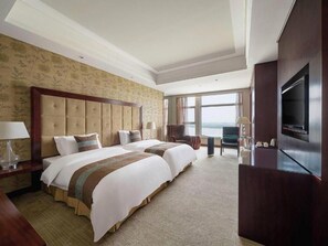 A hotel room with two beds, a television, and a view of the sea. - Xinhua Jianguo Hotel Jiujiang (Jiujiang)
