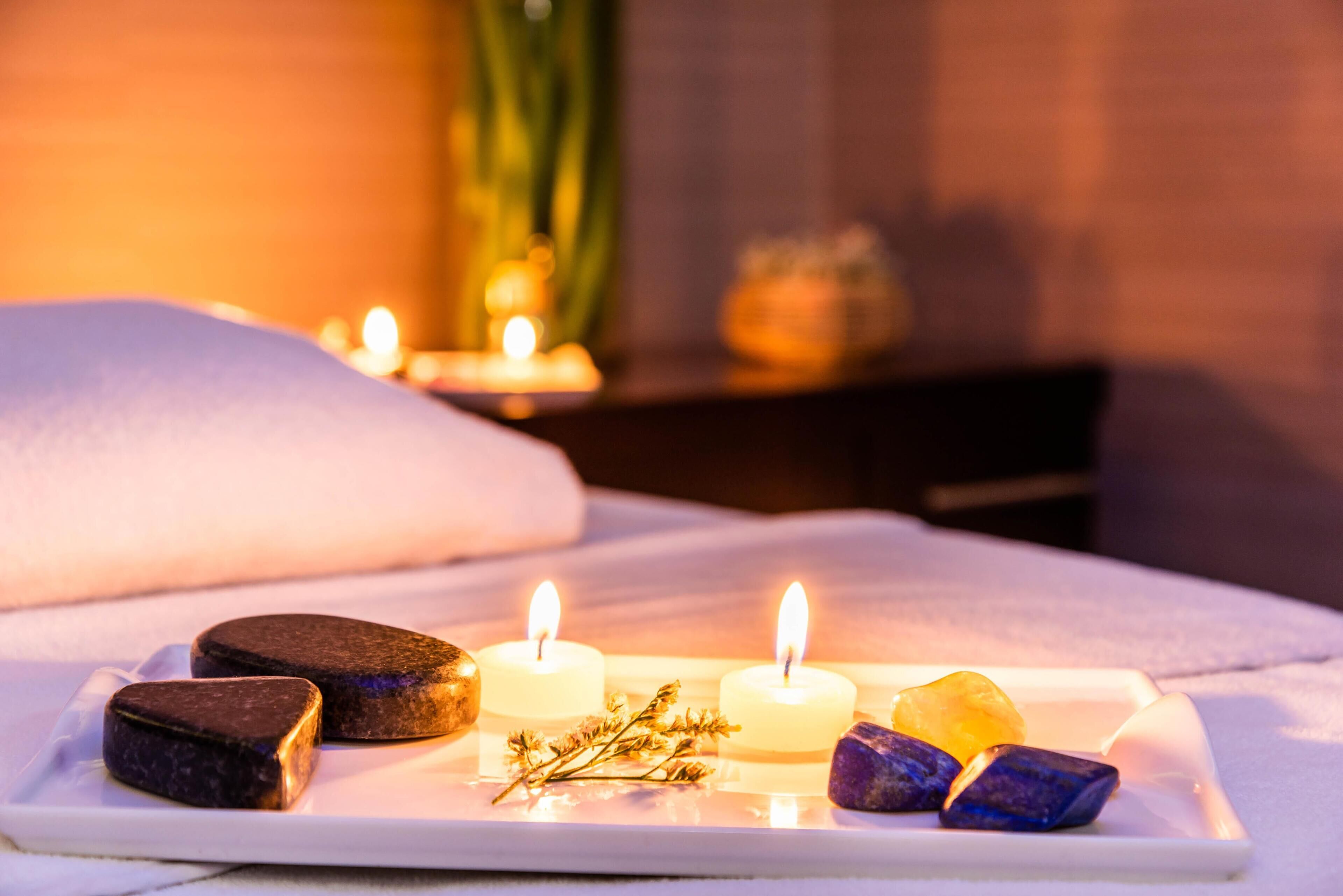 A spa setting with candles, stones, and a white pillow.