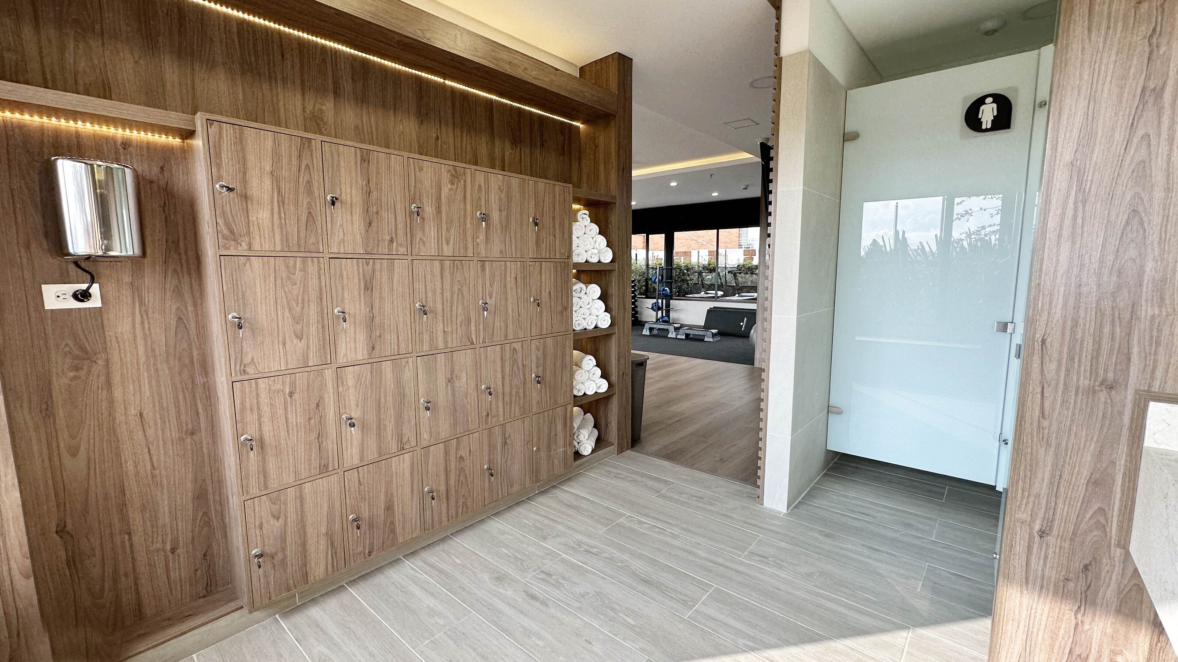 A wooden wardrobe with multiple compartments and a shelf with neatly rolled towels.