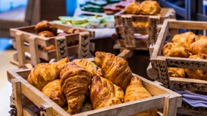 Exposição de uma padaria com diversos produtos de panificação, incluindo croissants, em caixas de madeira.