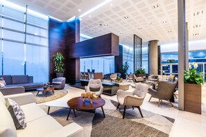 Un vestíbulo espacioso con mobiliario moderno, ventanas amplias y una zona de estar central.