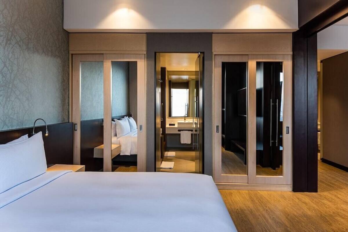 Een moderne hotelkamer met een groot bed, een inloopkast, een badkamer met spiegel en een douche.