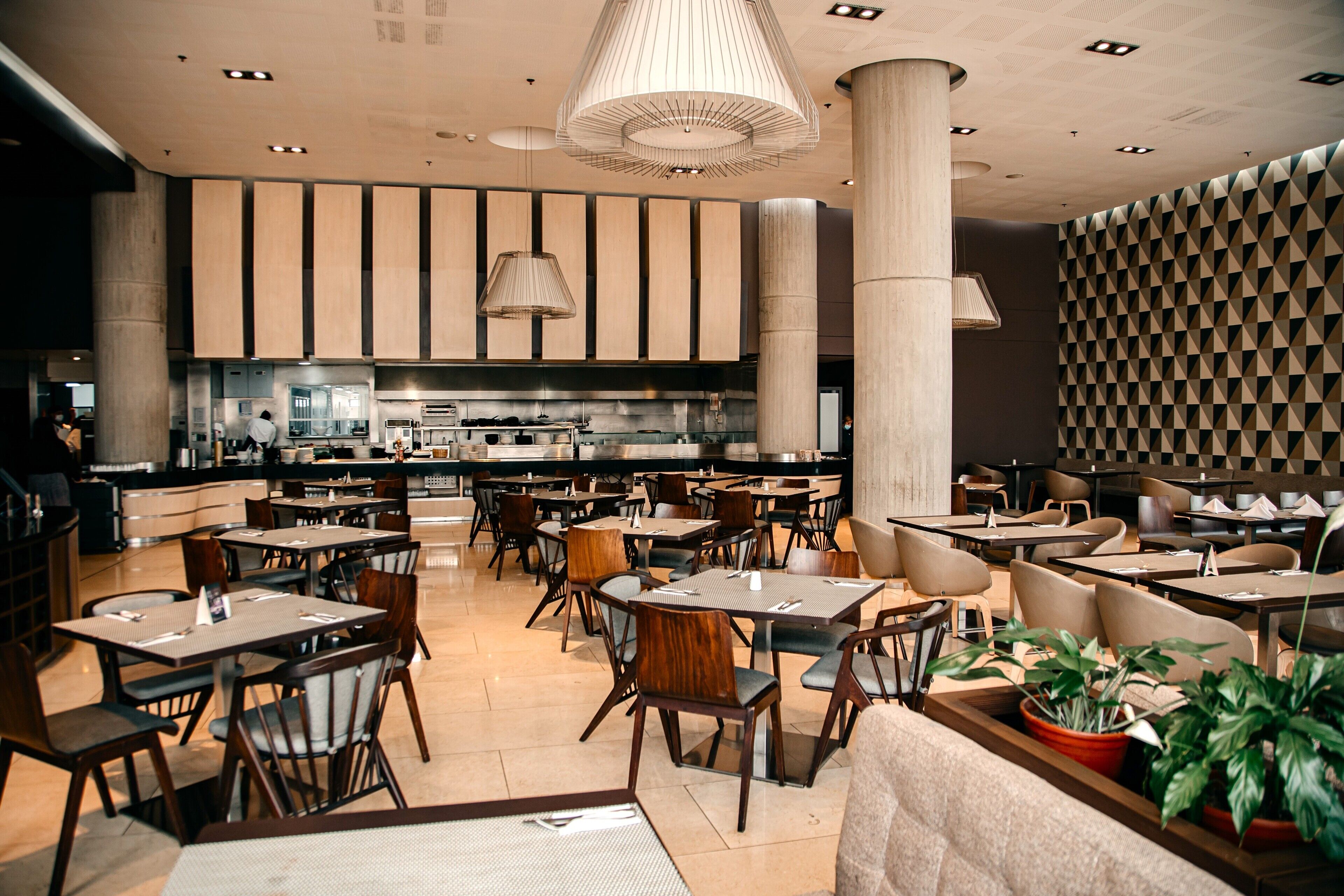 Un restaurante moderno con techos altos, ventanas amplias y una zona de cocina central.
