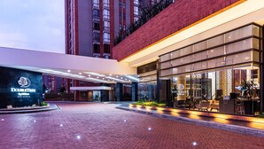 Entrada de hotel con diseño moderno, un letrero visible que dice 'DoubleTree' y un camino de ladrillo que conduce a la entrada.