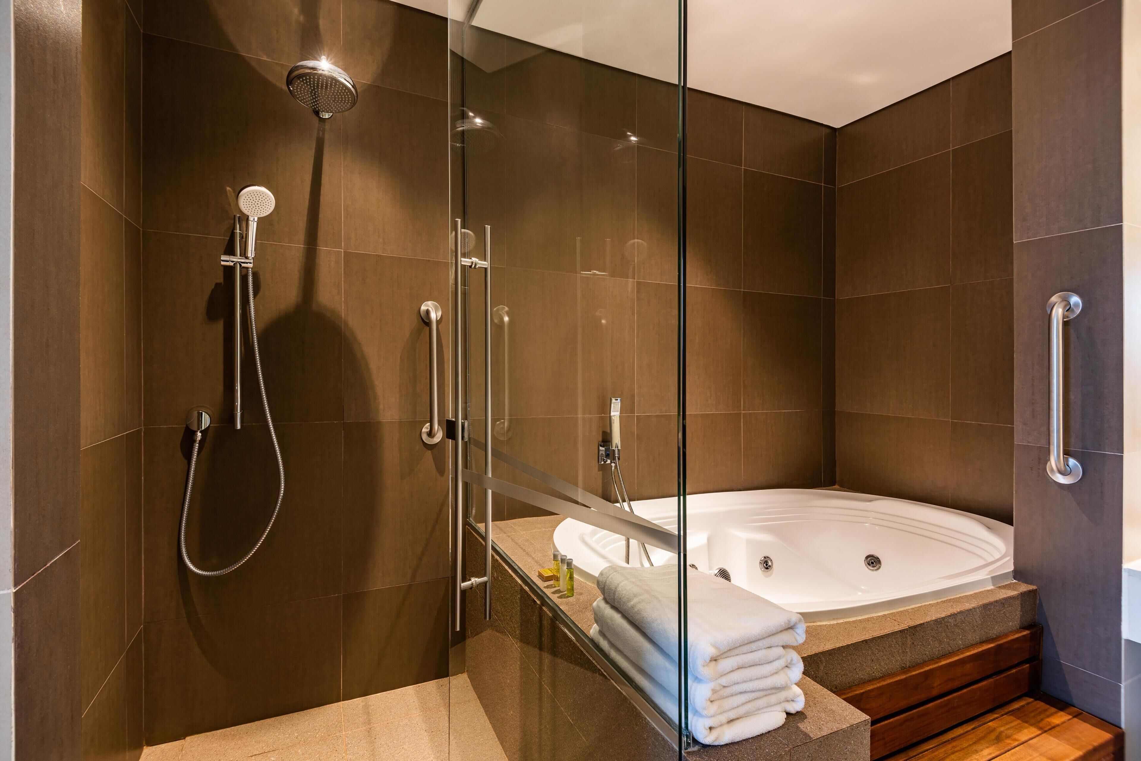 A modern bathroom with a glass-enclosed shower, a standalone bathtub, and a vanity with a towel rack.