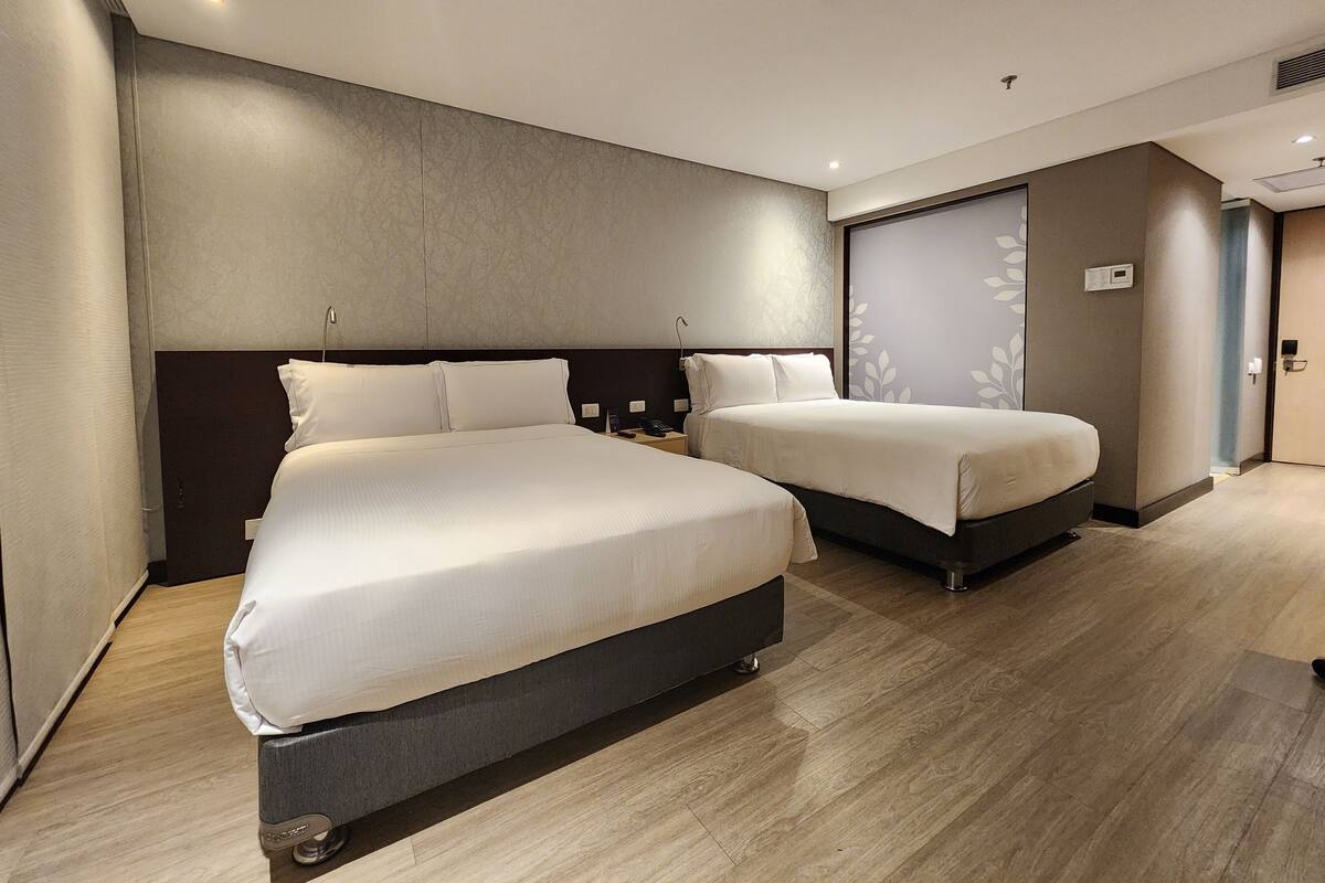 A hotel room with two beds, a large mirror, and a wardrobe.