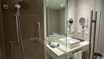 A modern bathroom with a glass shower enclosure, a white sink, and a large mirror.