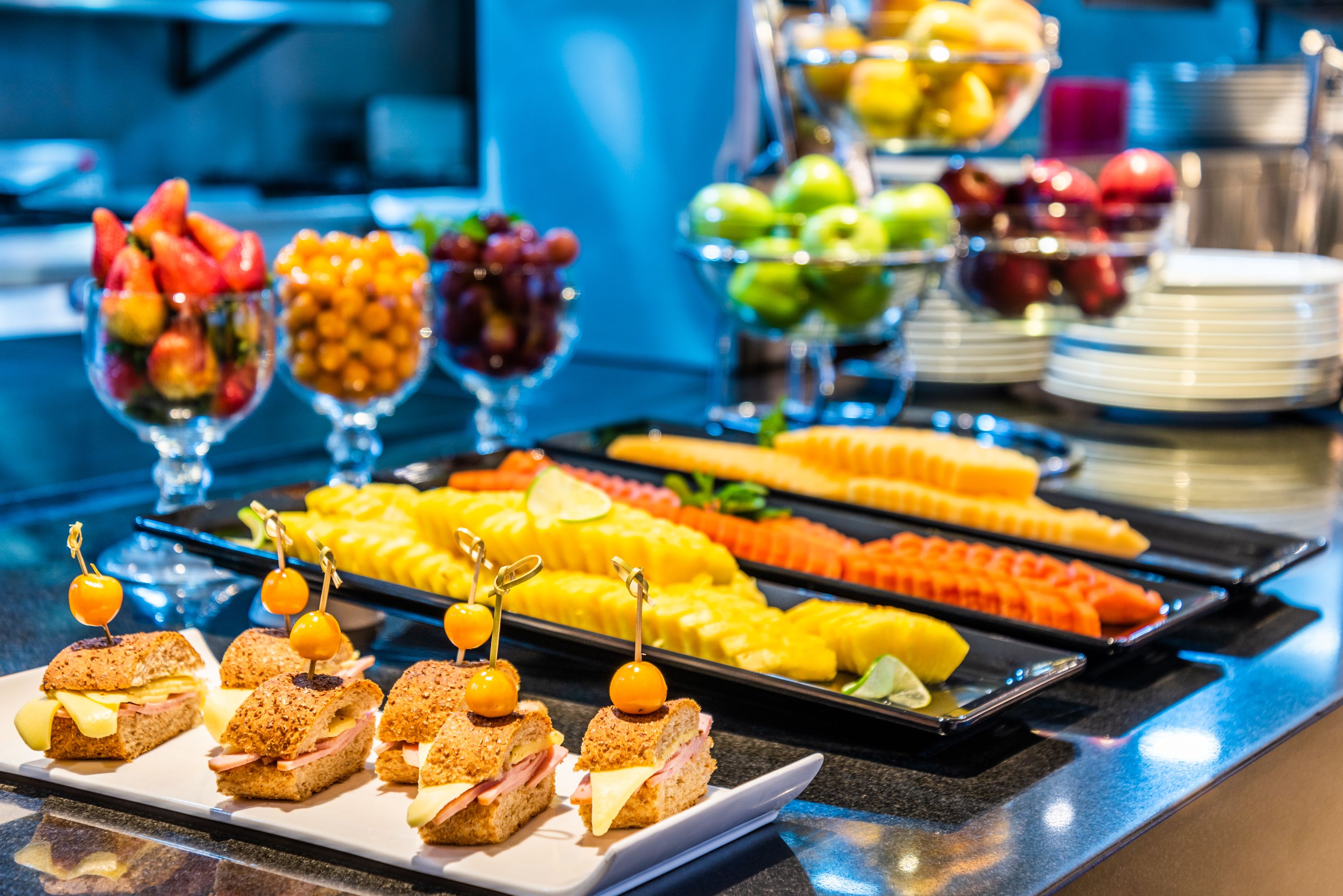 Een buffet met diverse gerechten, zoals belegde broodjes, fruit en groenten.