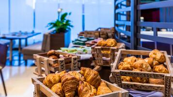 A bakery display with various pastries in wooden crates, a seating area with tables, and a large window with a view.