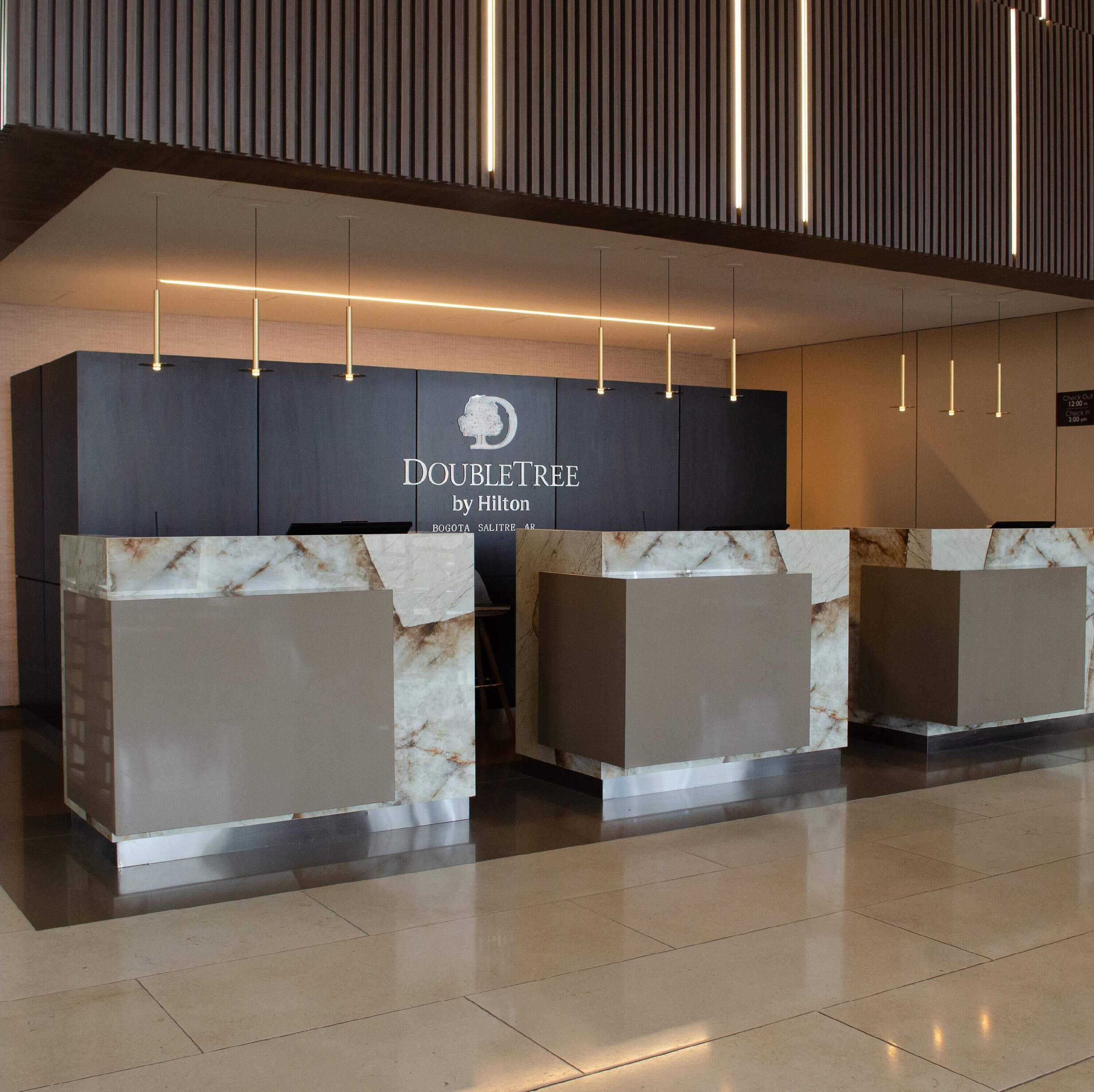 A hotel reception desk with a modern design, featuring a marble counter and a sign that reads 'DOUBLETREE by Hilton'.