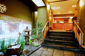 A traditional Japanese interior with a wooden staircase, a stone lantern, and a small garden area. - Togetsutei (Kyoto)