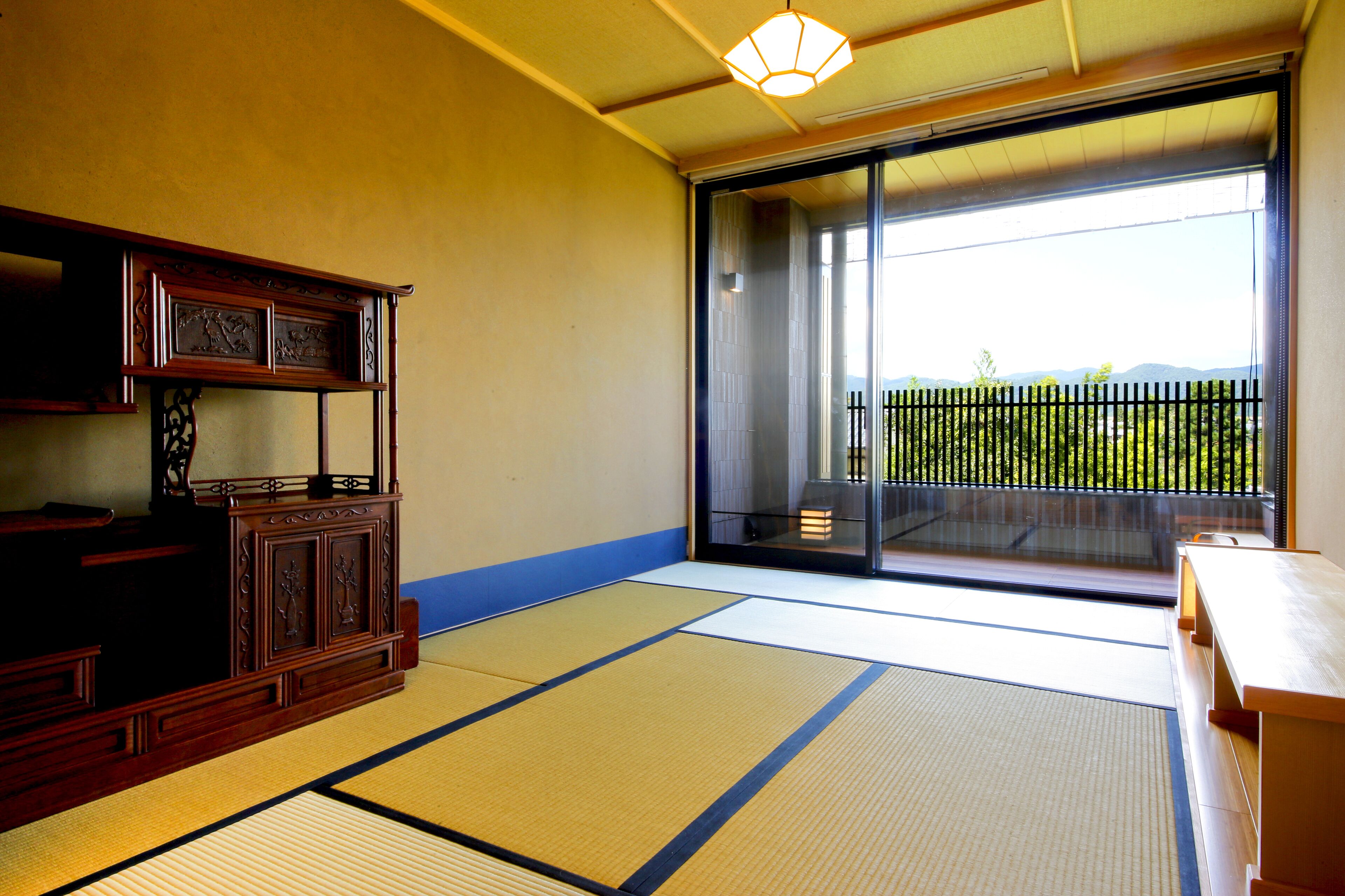 A traditional Japanese room with tatami flooring, a sliding door leading to a balcony, and a wooden cabinet.