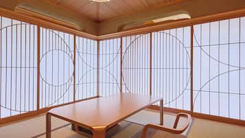 A traditional Japanese room with tatami flooring, a low table, and a chair.