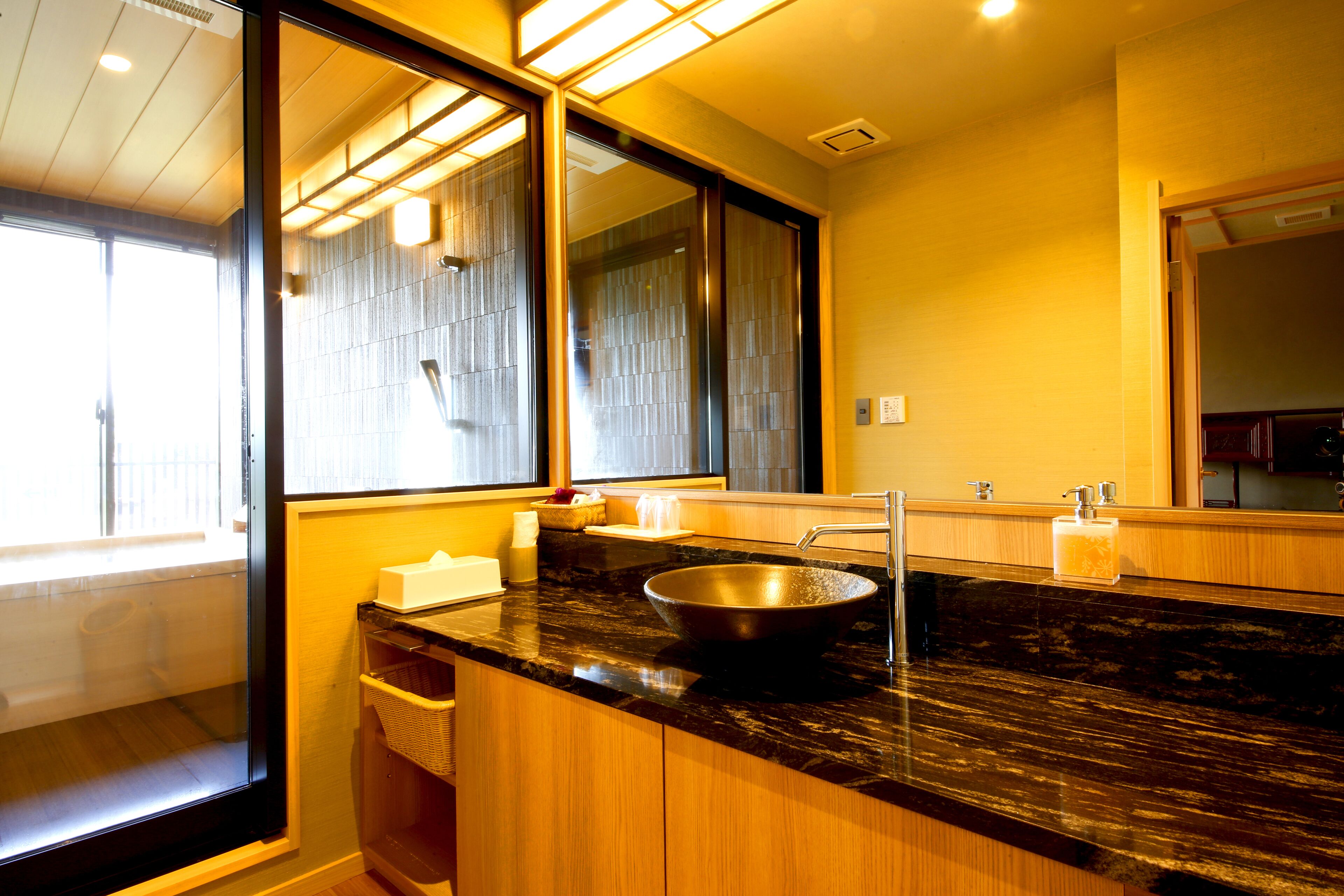 A modern bathroom with a large mirror, a black sink, and wooden cabinets.