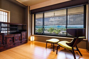 A room with a large window, a wooden cabinet, and a modern chair. - Togetsutei (Kyoto)