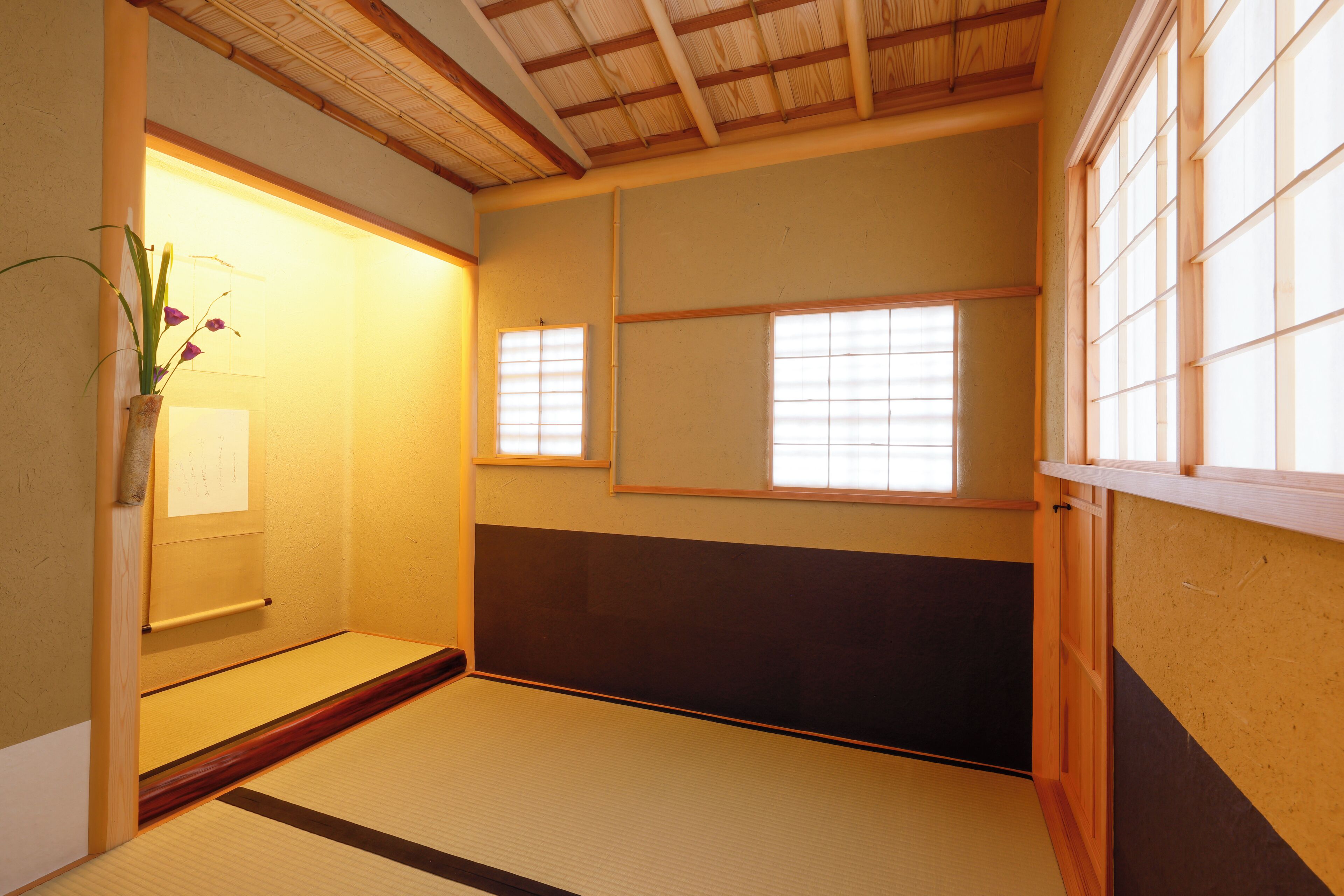 A traditional Japanese room with tatami flooring, shoji screens, and a wooden ceiling.