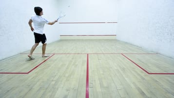 Una cancha de squash con piso de madera y líneas rojas que delimitan el área de juego.