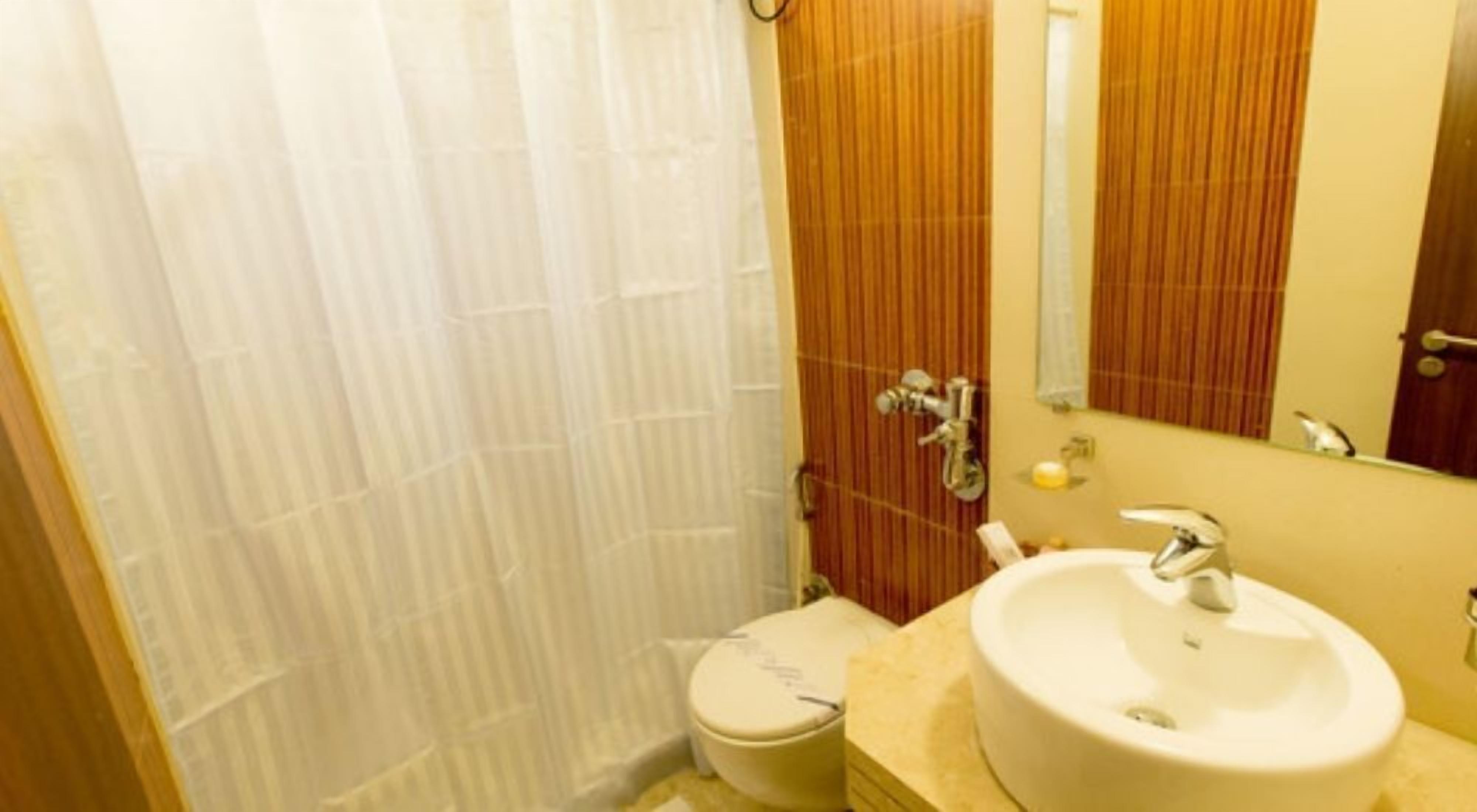 A bathroom with a toilet, sink, and mirror.