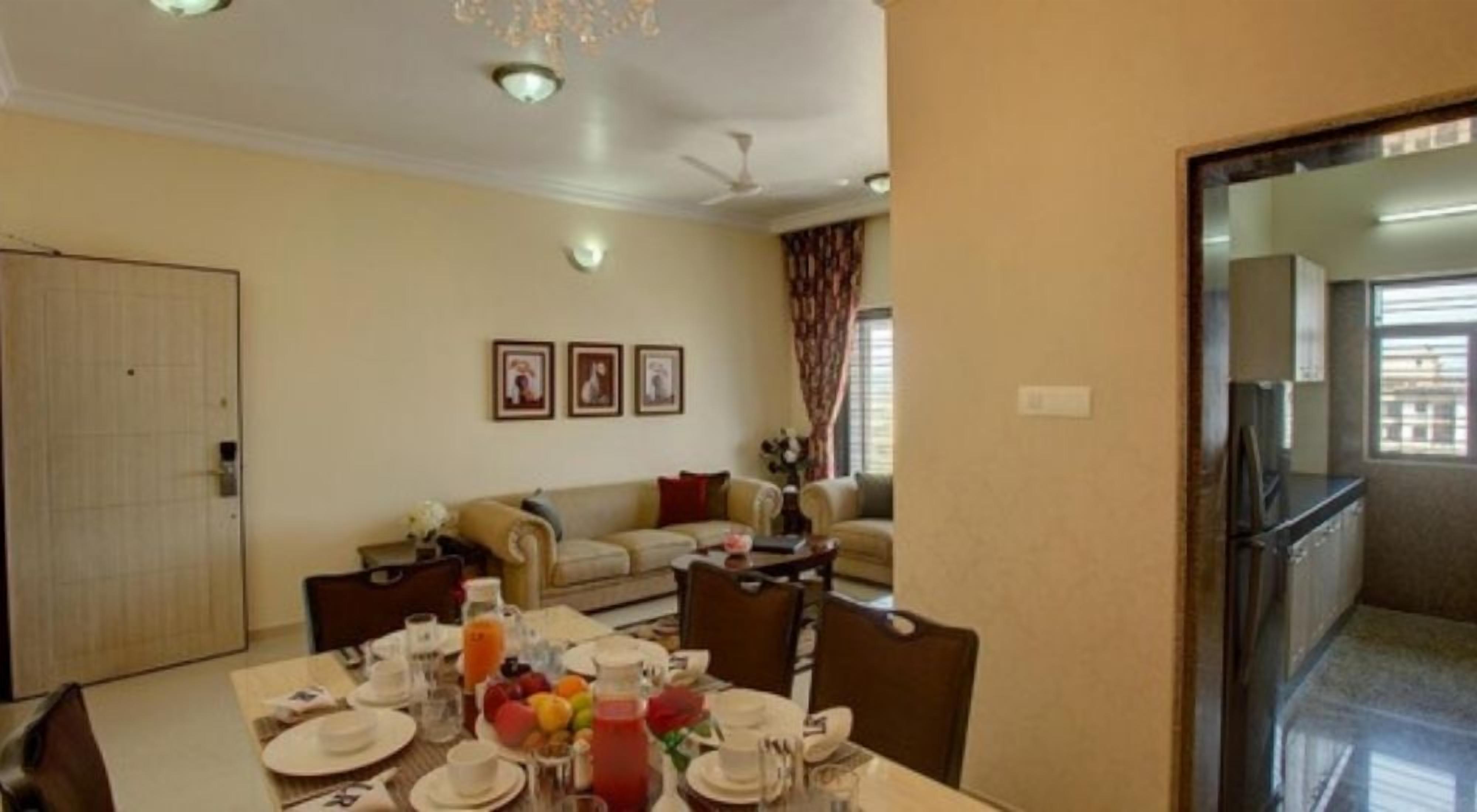 A dining area with a table set for four, a sofa, and a kitchen visible in the background.