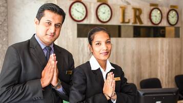 Two individuals in business attire standing in a lobby with clocks and a sign that reads "LRO".
