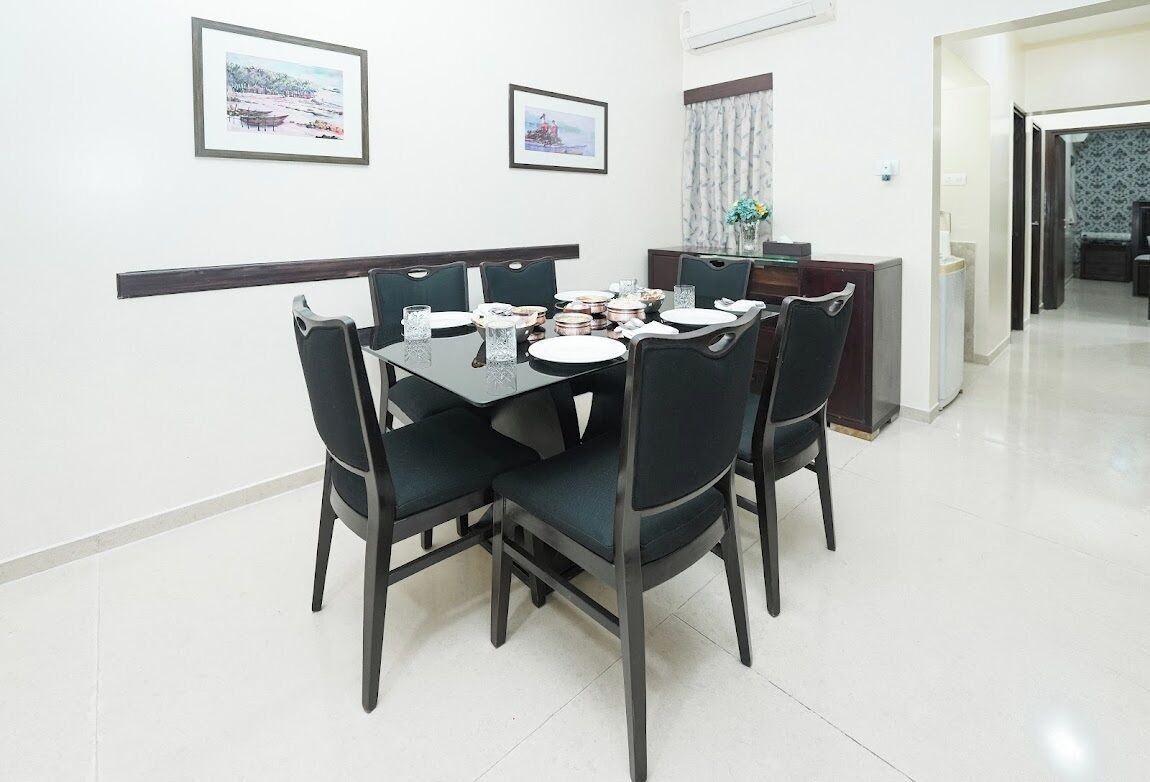 Un coin repas comprenant une table rectangulaire, quatre chaises et deux tableaux encadrés accrochés au mur.