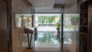 A modern lobby with a glass entrance, a reception desk, and a view of the outdoors. - Lalco Residency (Mumbai)