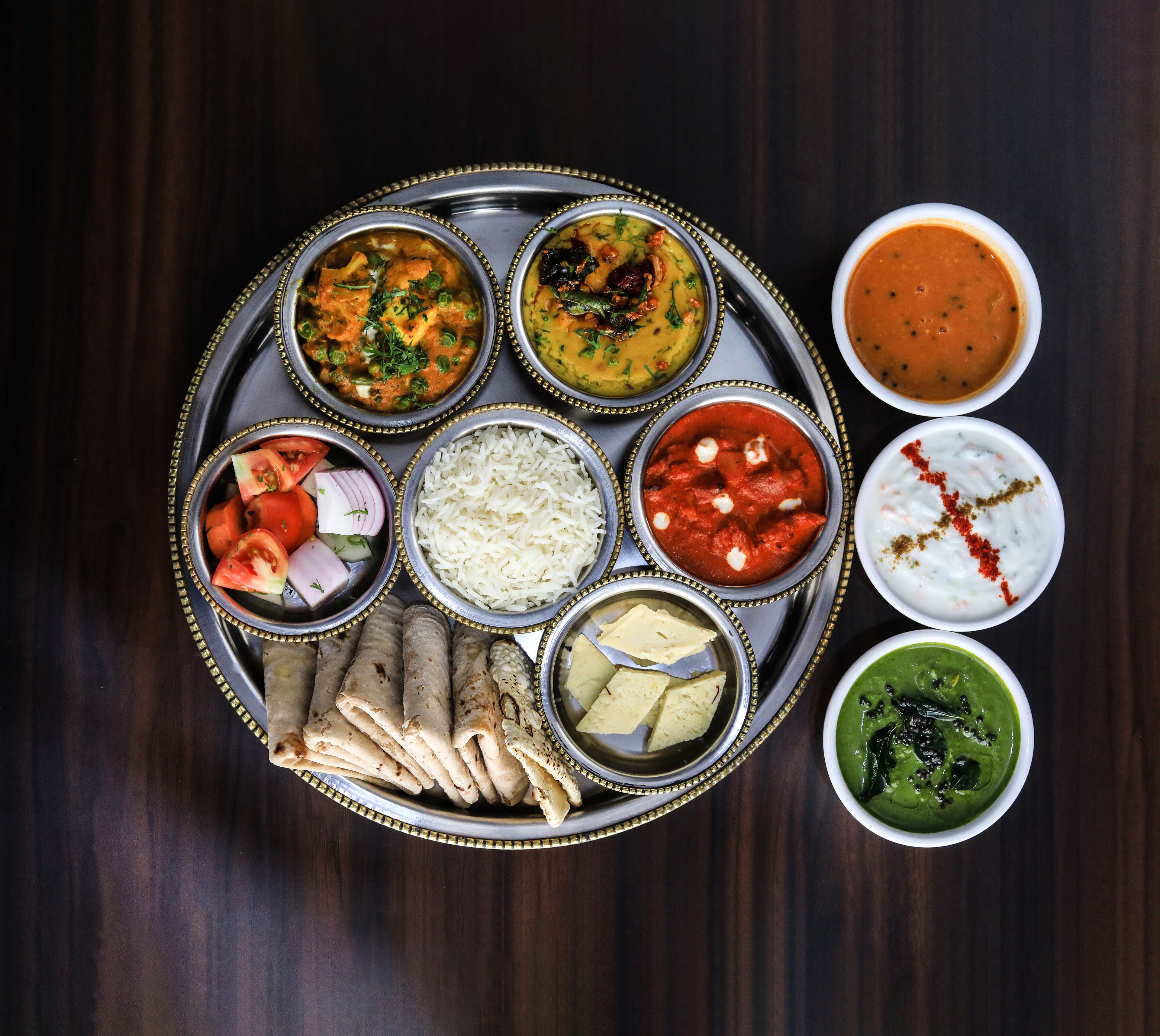 A traditional Indian meal with various dishes on a metal tray.
