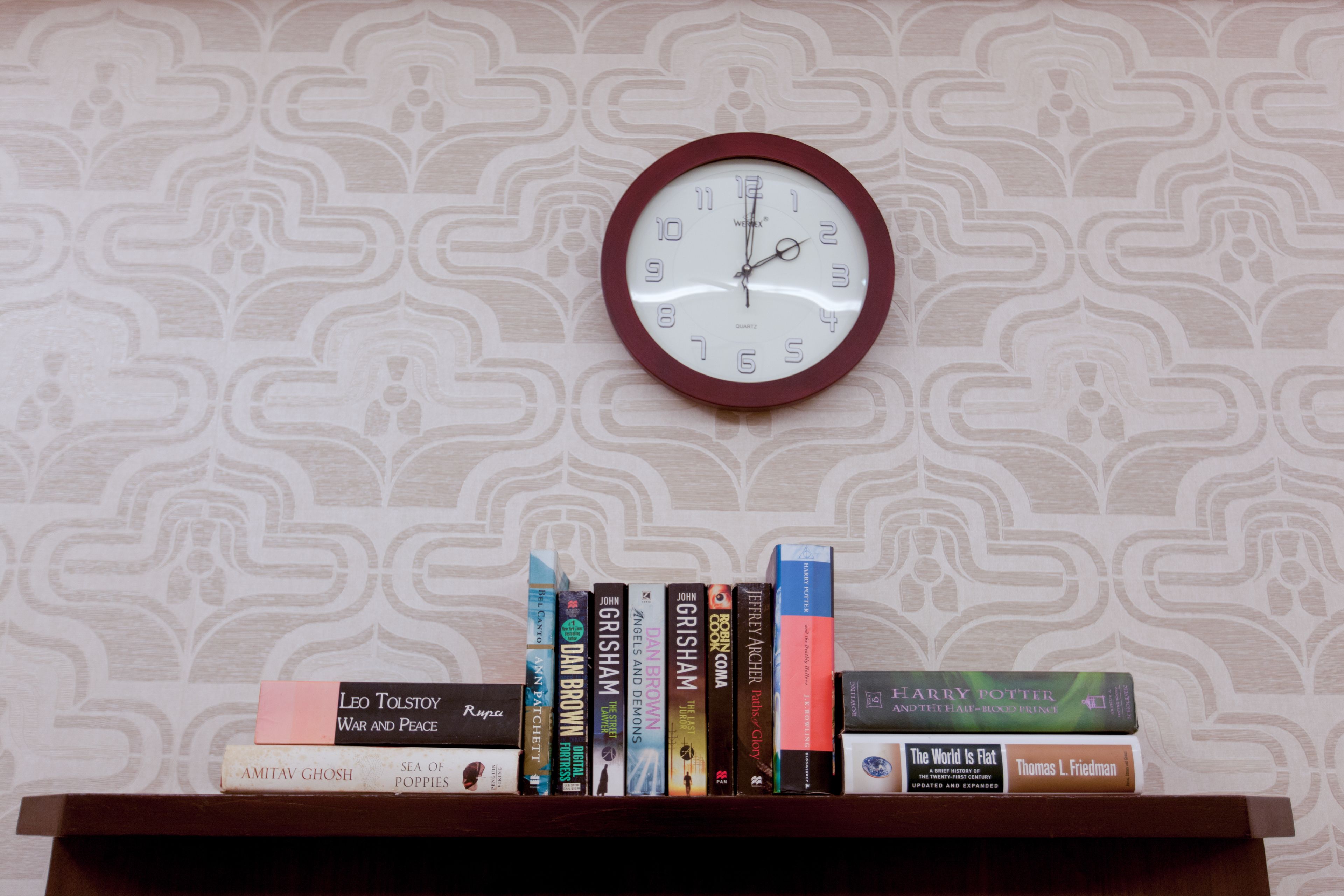 A bookshelf with books and a clock on the wall.