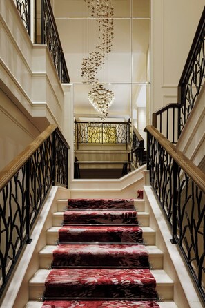 A grand staircase with ornate black railings and a red carpeted landing.