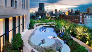 A landscaped courtyard with a circular water feature, surrounded by trees and a building with large windows. - The St. Regis Osaka (Osaka)