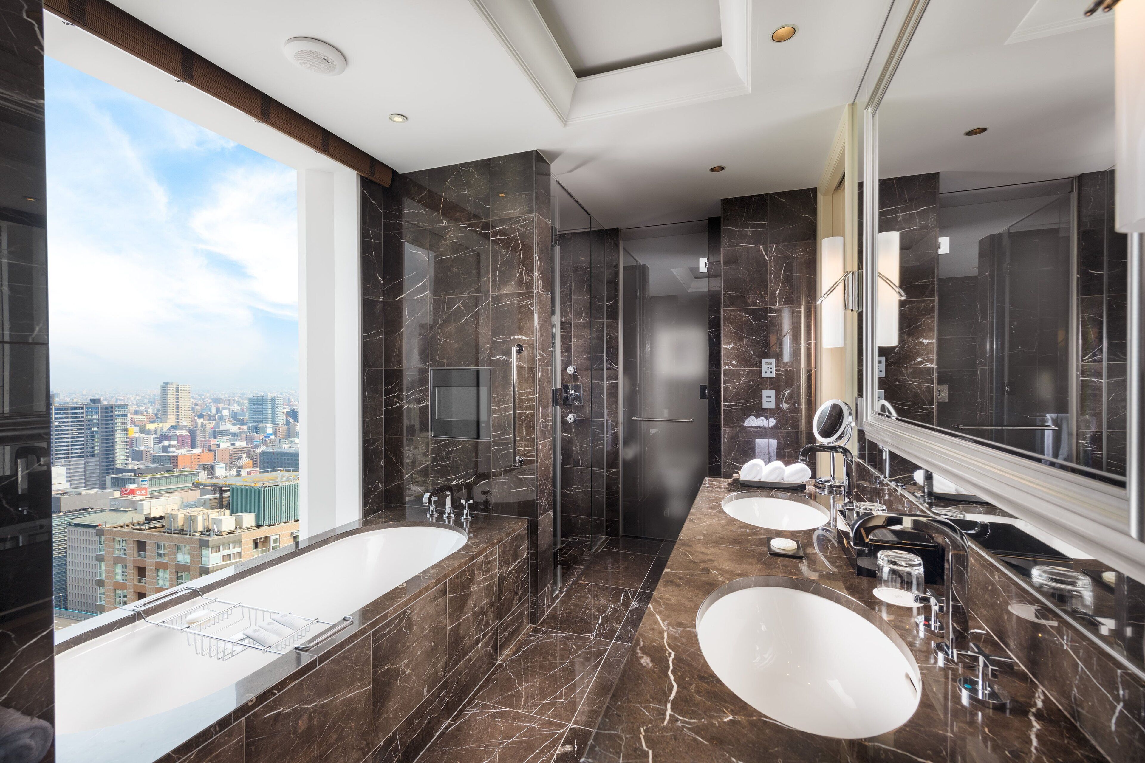 A modern bathroom with two sinks, a large mirror, and a shower.