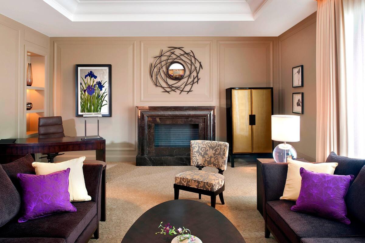 Una sala de estar con chimenea, dos sofás, un sillón y una mesa de centro.