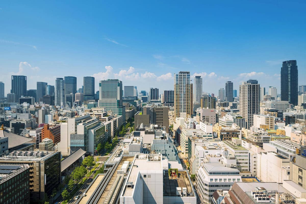 A cityscape with modern high-rise buildings, a mix of commercial and residential structures, and a clear blue sky.