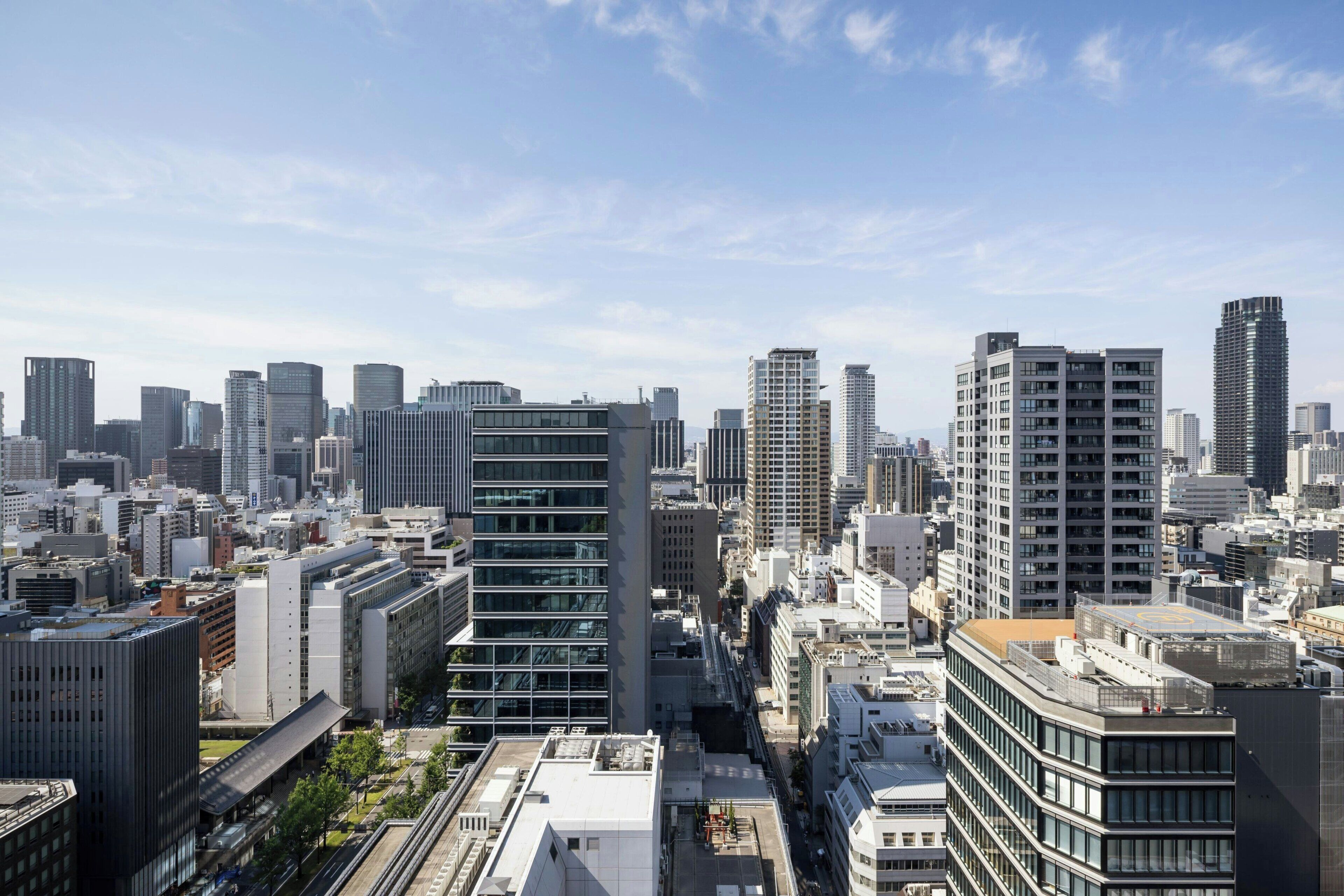 Paisagem urbana com edifícios altos e modernos, céu limpo e uma combinação de construções comerciais e residenciais.