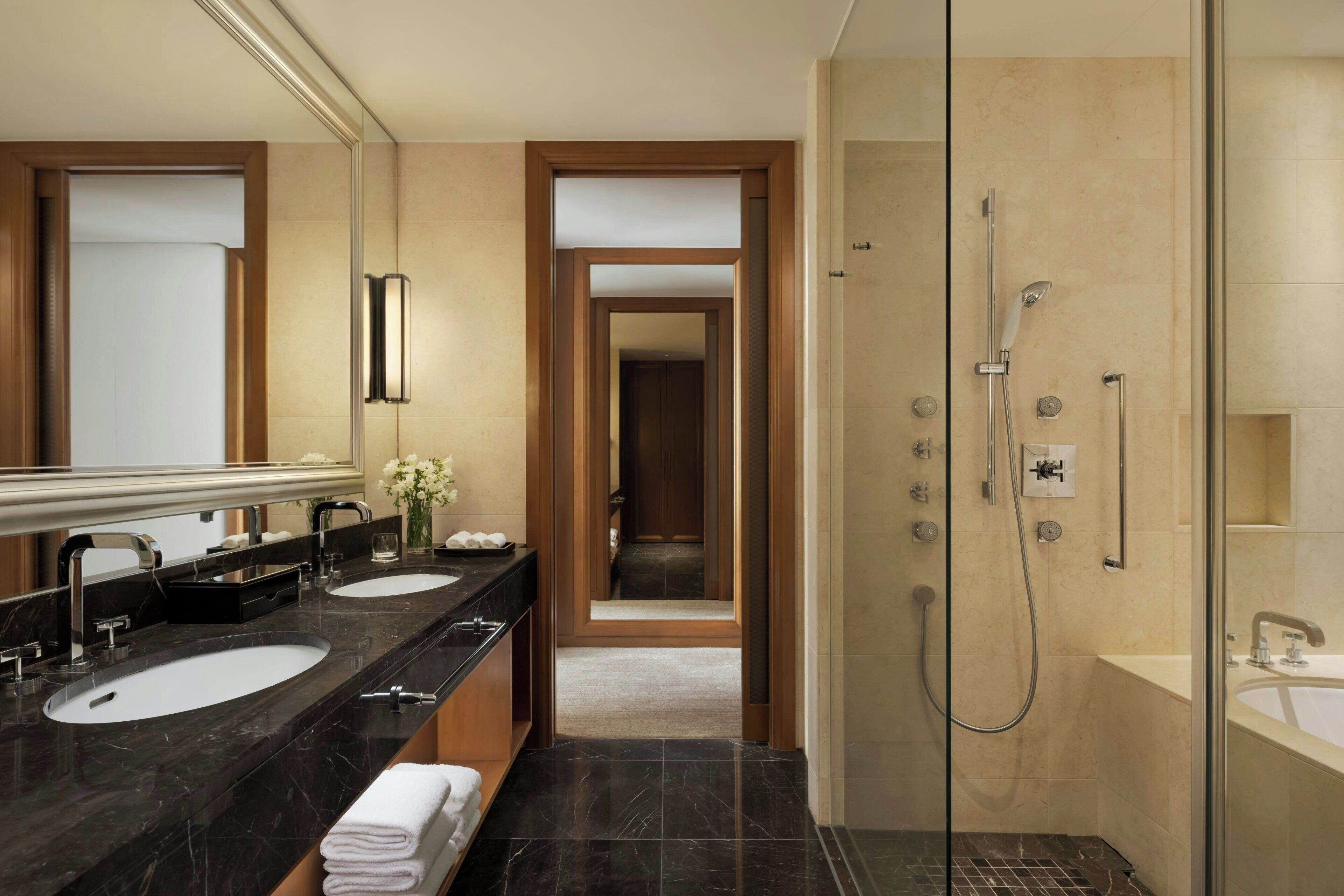 A modern bathroom with two sinks, a shower, and a mirror.
