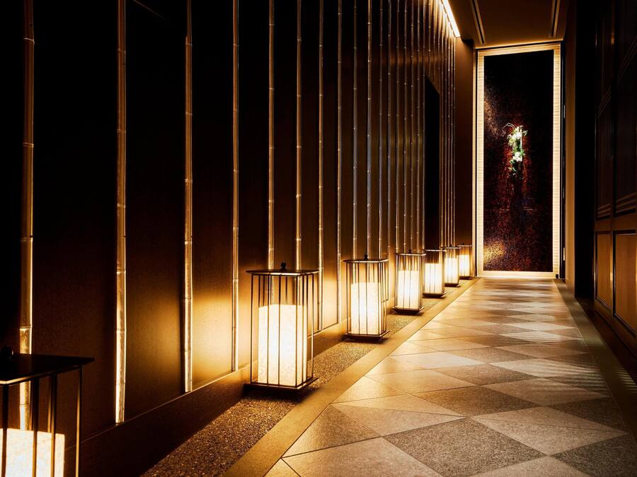 Un pasillo con luminarias verticales iluminadas y piso estampado.